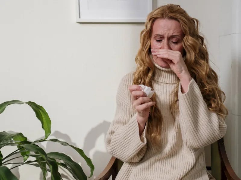 Kvinna med gräsallergi nyser och är snuvig. Få behandling mot gräsallergi online. ReceptOnline.se